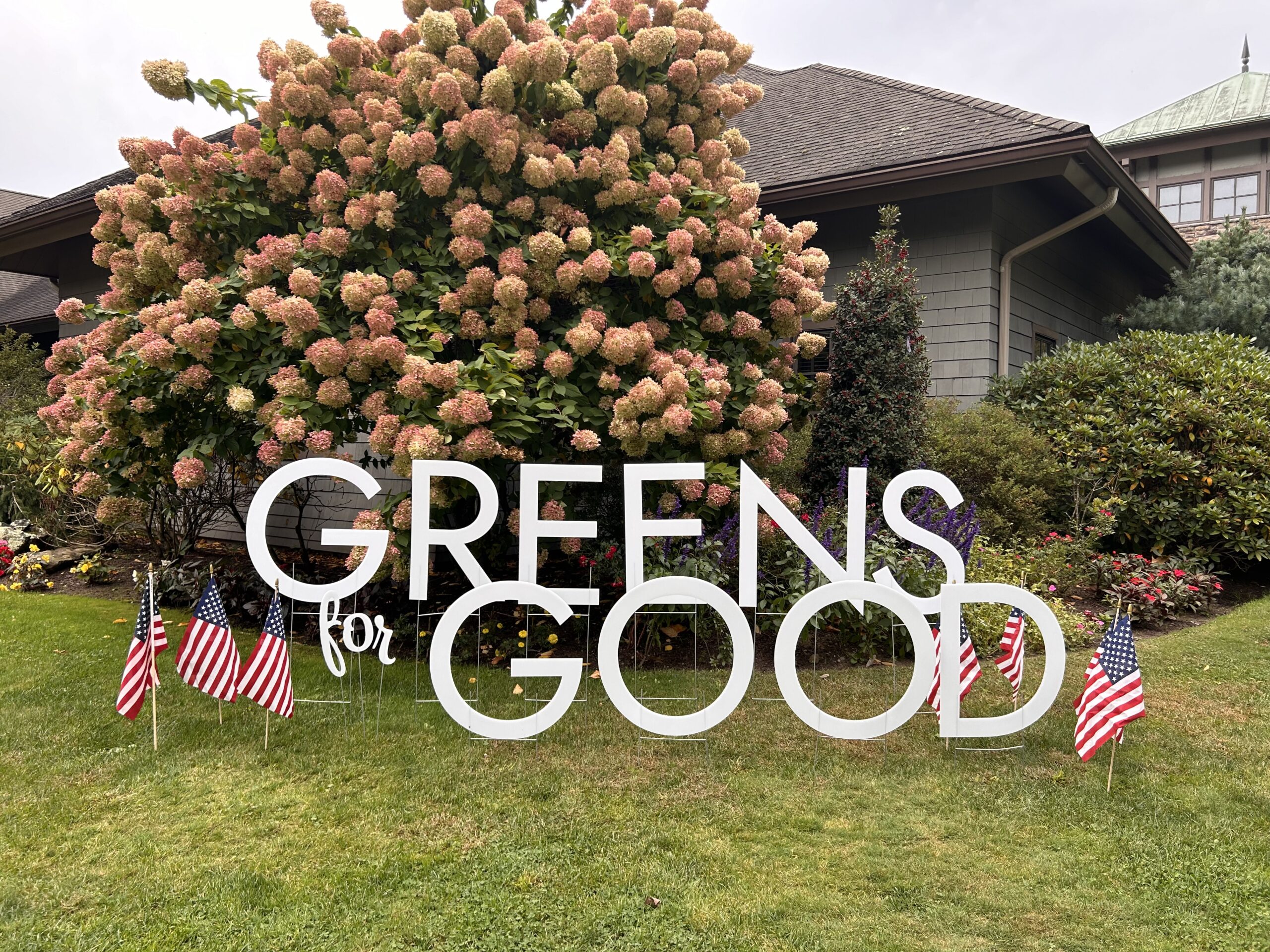 Greens for Good Sign in front of blooming tree